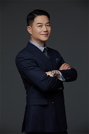 Professional portrait of a man in a navy pinstripe suit with arms crossed against a dark studio backdrop, looking confidently at the camera.