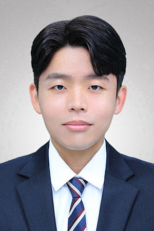Professional headshot of a young man in a navy suit and striped tie against a neutral background.