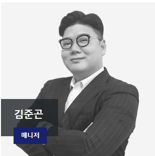 Portrait of Kim Jun-gon, manager, wearing a pinstripe suit and glasses with arms crossed.