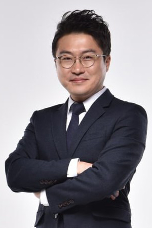Professional portrait of a man in a dark suit and glasses, arms crossed, smiling at the camera.