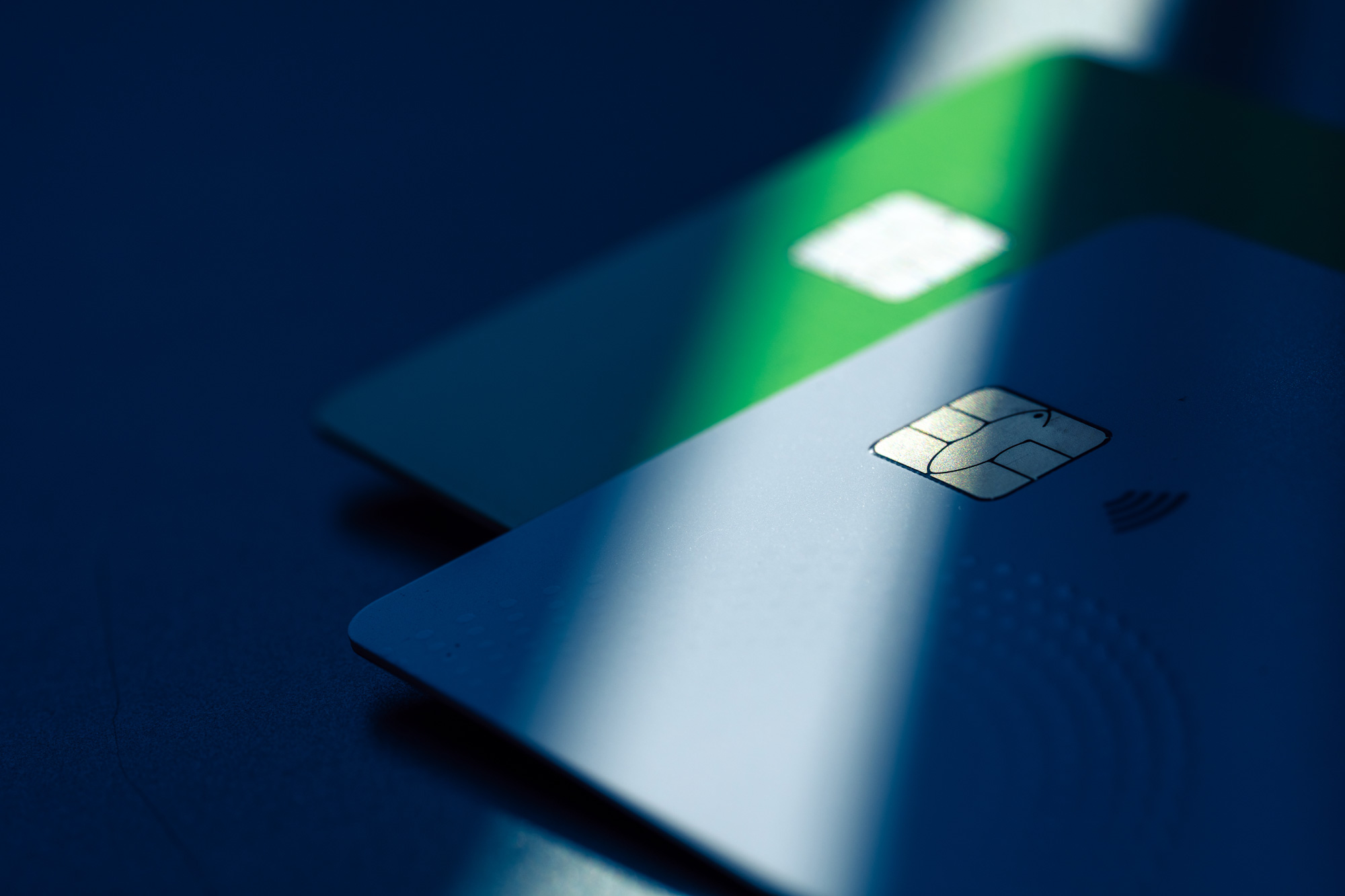 Close-up of a plastic payment card with a chip on a blue-toned surface.